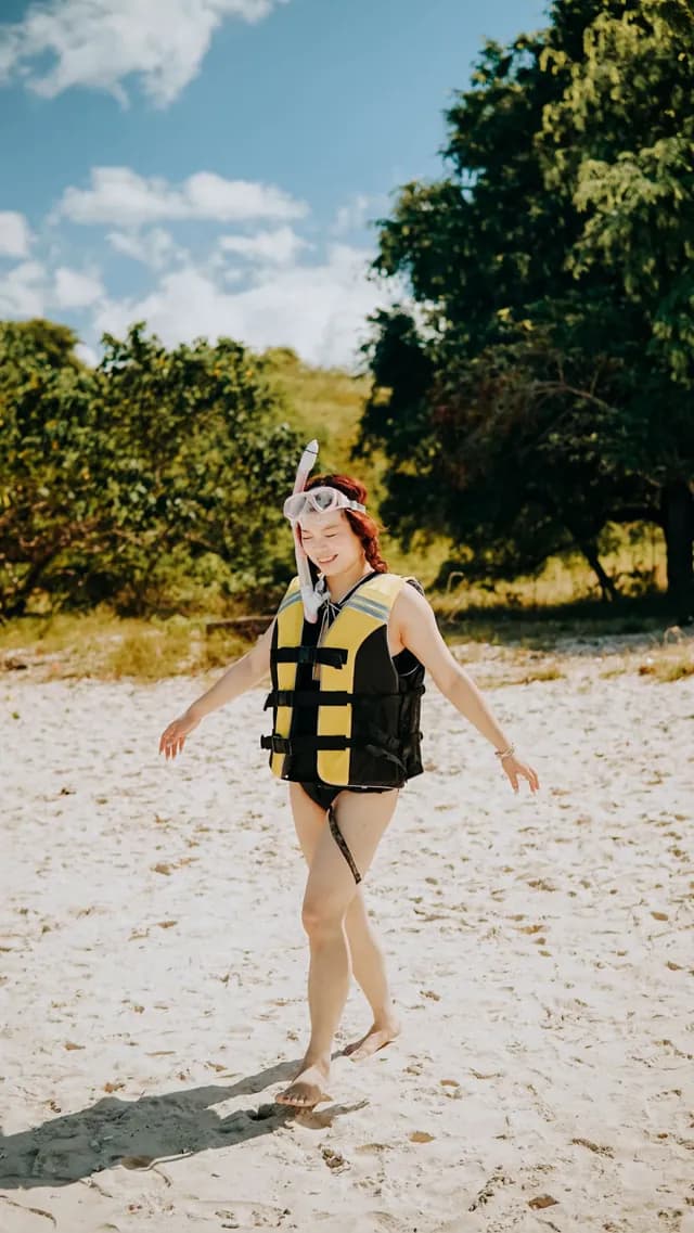 Traveler with snorkeling gear and life vest on the beach